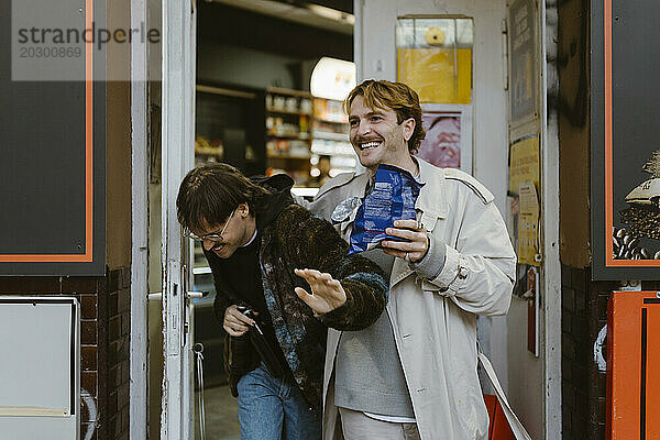 Glückliches schwules Paar  das beim Verlassen des Supermarkts lacht