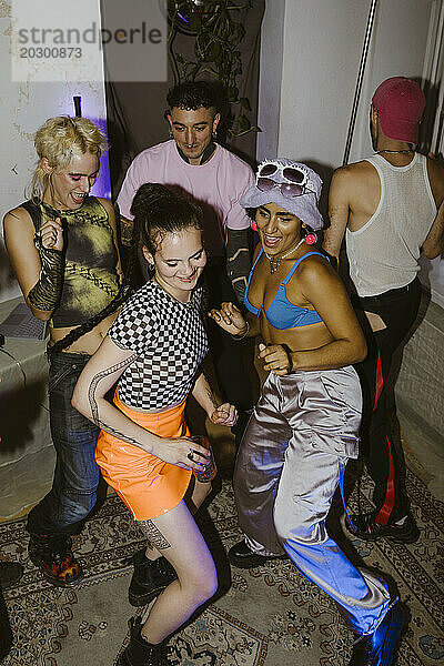 Fröhliche nicht-binäre Freunde tanzen miteinander im Nachtclub