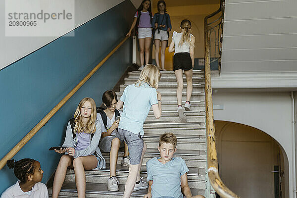 Männliche und weibliche Schüler auf der Treppe während der Pause in der Schule