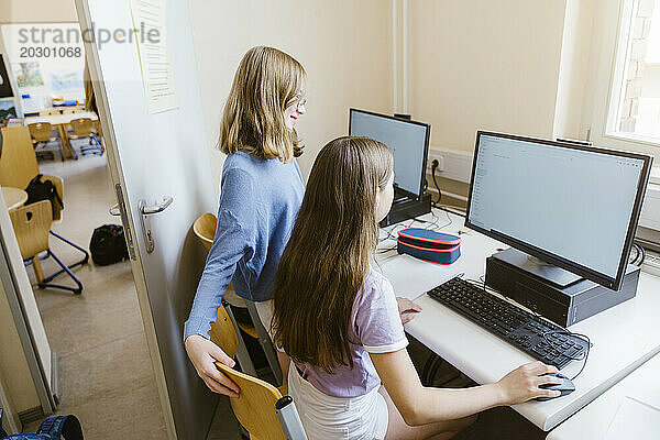 Studentinnen surfen am Computer am Schreibtisch im Klassenzimmer im Internet