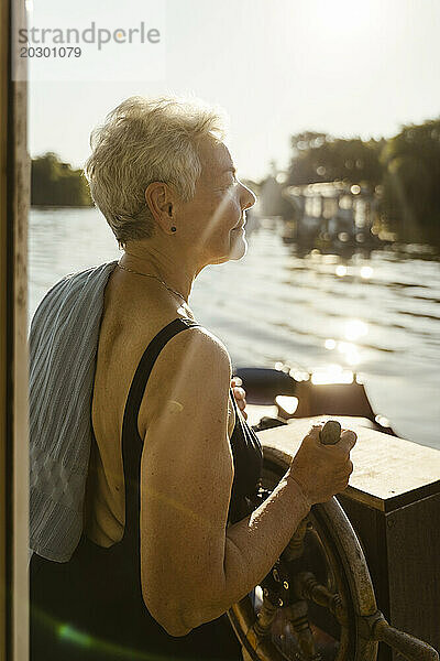 Ältere Frau steuert Hausboot im Urlaub