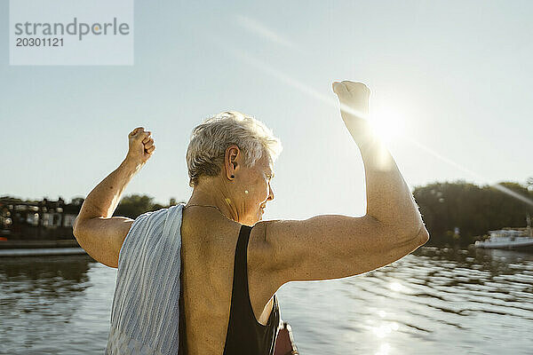Ältere Frau lässt im Urlaub an einem sonnigen Tag auf dem Hausboot ihre Muskeln spielen