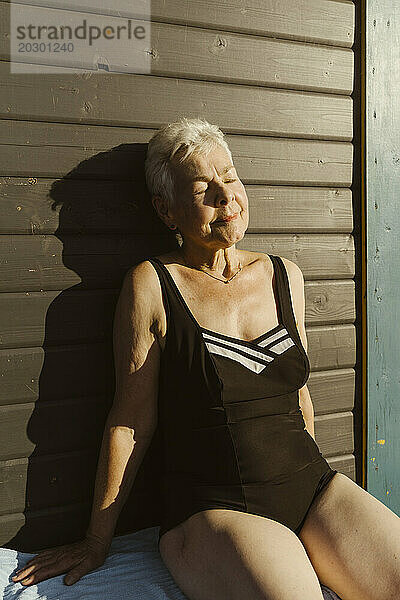 Ältere Frau sonnt sich  während sie mit geschlossenen Augen auf einem Hausboot sitzt