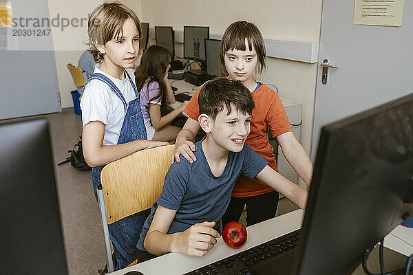 Männliche und weibliche Schüler mit Down-Syndrom  Mädchen benutzen Computer am Schreibtisch im Klassenzimmer