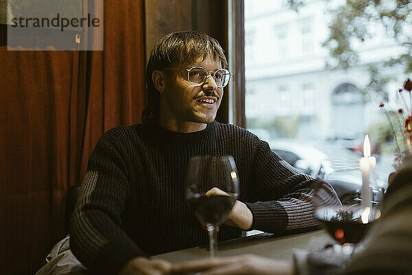 Schwuler Mann trägt eine Brille und unterhält sich mit seinem Freund  während er im Restaurant sitzt