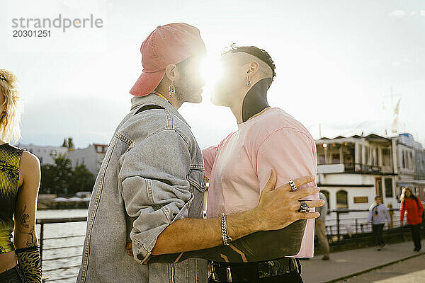 Seitenansicht eines romantischen schwulen Mannes  der einen nicht-binären Freund auf der Promenade küsst