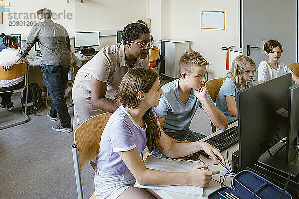 Männliche und weibliche Lehrer unterstützen Schüler im Computerunterricht in der Schule