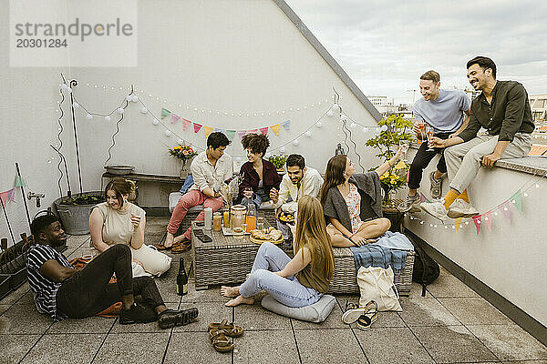 Gruppe gemischtrassiger Freunde  die Spaß beim Feiern während der Party auf dem geschmückten Balkon haben
