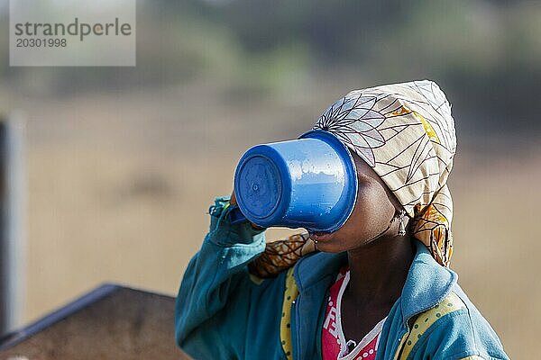 Junge Frau  Mädchen trinkt aus einem Plastikbecher Wasser in der Gemeinde Maraban Dare im Bundesstaat Plateau in Nigeria  07.02.2024
