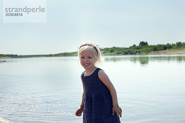 Porträt eines fröhlichen kleinen Mädchens  das sich am See ausruht