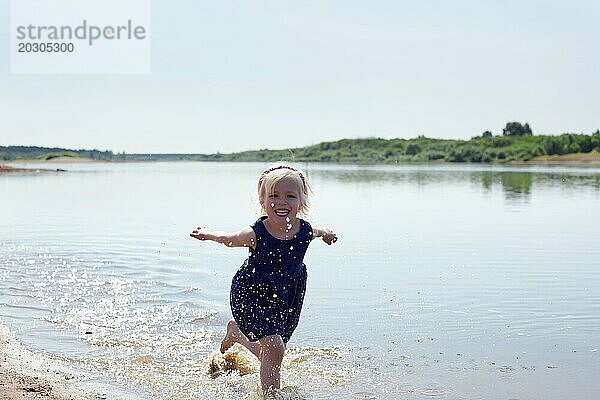 Fröhliches junges Mädchen läuft am Flussufer entlang