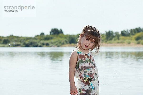 Lächelndes kleines Mädchen posiert am Fluss  Nahaufnahme