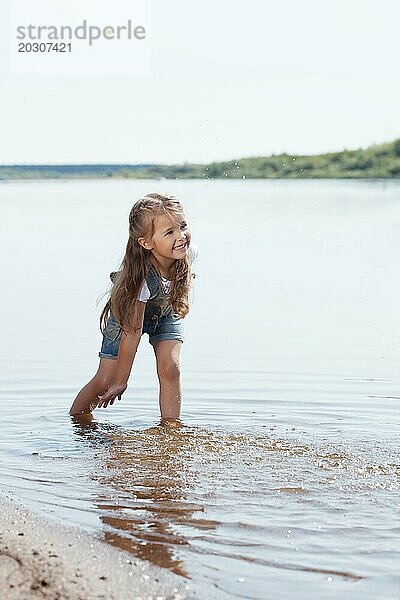 Bild von fröhlichen kleinen Mädchen spielen im See