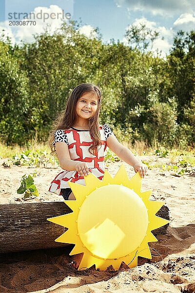 Fröhliches kleines Mädchen spielt mit Papier Sonne im Park