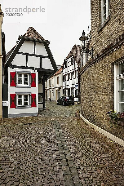 Historisches  kleines Fachwerkhaus und Backsteinfassade mit weißen Fenstern bei trübem Wetter in Warendorf  Kreis Warendorf  Nordrhein-Westfalen  Deutschland  Europa