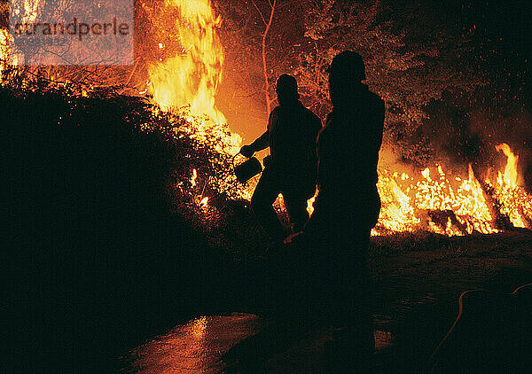 Australien. Silhouette von Feuerwehrleuten  die ein Buschfeuer bekämpfen