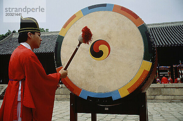 Südkorea. Königlicher konfuzianischer Schrein Jongmyo. Mann schlägt einen zeremoniellen Gong an.