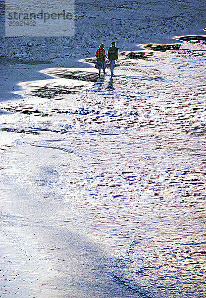 Australien. Paar in Alltagskleidung geht am Strand spazieren.