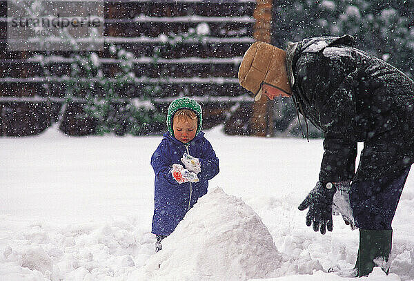 Kanada. Ontario. Mutter und Kind bauen draußen einen Schneemann.