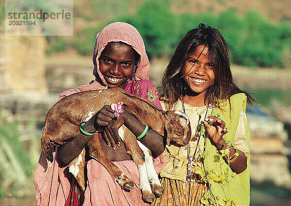 Indien. Rajasthan. Udaipur. Nathdwara. Kinder im ländlichen Raum. Zwei Mädchen mit einer Ziege.