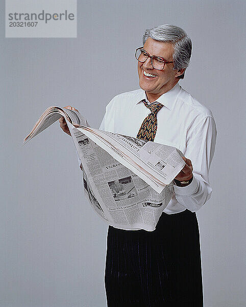 Wirtschaft und Berufe. Älterer Mann drinnen  hält eine Broadsheet-Zeitung in der Hand.