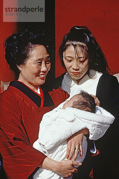 Japan. Stadt Tokio. Zwei Frauen mit einem Baby im Freien.