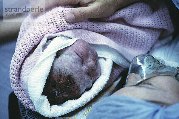 Medizinisches Krankenhaus. Geburt. Nahaufnahme eines neugeborenen Babys in den Armen der Mutter.