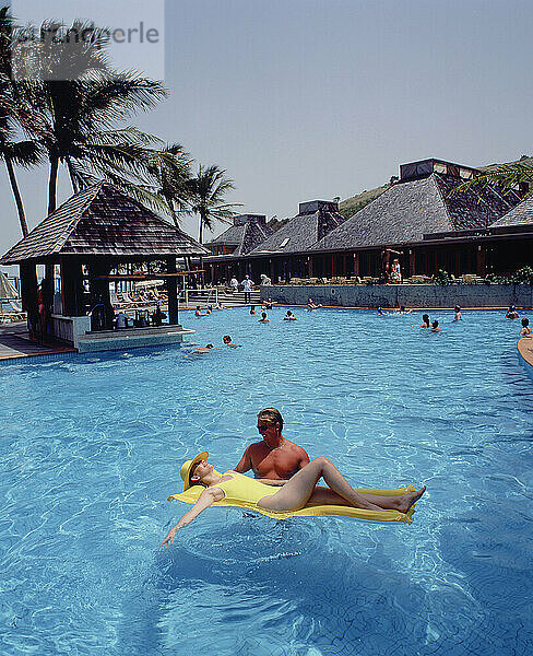 Australien. Queensland. Lindeman Island Resort. Junger Mann und junge Frau entspannen sich auf einer Lilo im Schwimmbad.