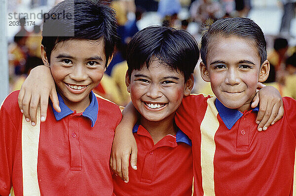 Singapur. Parade zum Nationalfeiertag. Außenporträt von drei Jungen.