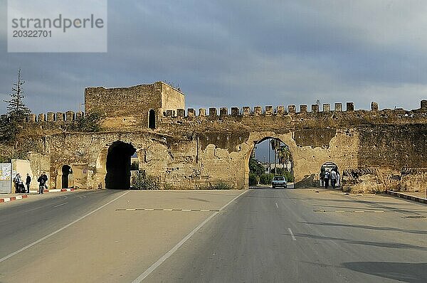Teile der Stadtmauer  Mausoleum Mulay Ismail  Meknes  Ein antiker Festungswall mit Torbogen über einer belebten Straße an einem bewölkten Tag  Nordmarokko  Marokko  Afrika