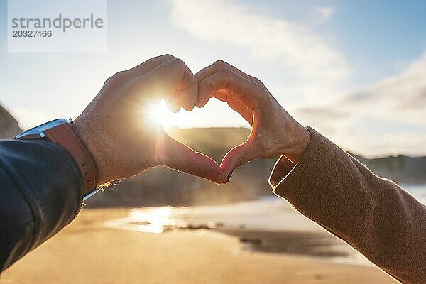 Nahaufnahme von Paar Hände machen Herzform in den Strand  im Herbst Saison. Glückliches Paar in der Liebe