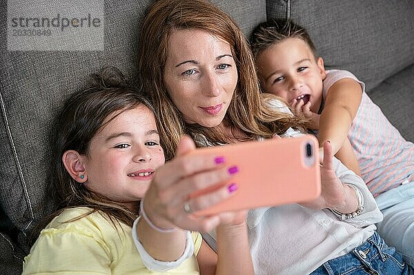 Glückliche Mutter mit ihren Kindern machen ein Selfie oder Videoanruf an Vater oder Verwandte in einem Sofa. Konzept der Technologie  neue Generation  Familie  Verbindung  Elternschaft. Hohe Qualität 4k Filmmaterial