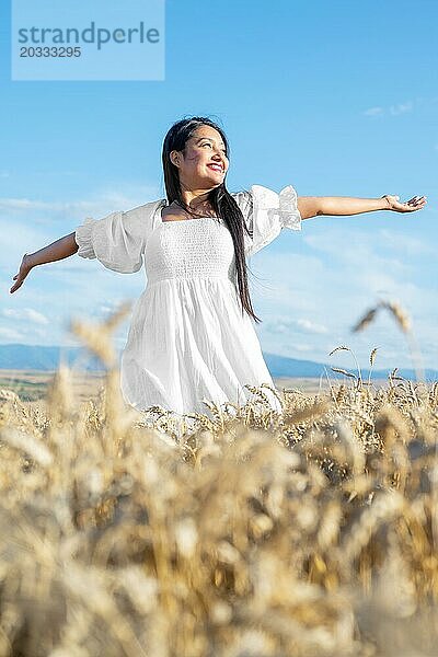 Porträt einer glücklichen jungen Frau in einem weißen Kleid  auf einem Weizenfeld. Lifestyle und Glück Konzept. Frau mit offenen Armen  Foto in hoher Qualität