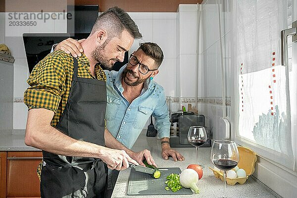 Happy Hipster Homosexuell Paar in der Liebe umarmt  während in der Küche stehen. Sie kochen Abendessen zusammen zu Hause und trinken Wein. Hohe Qualität Fotografie