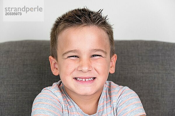 Porträt eines lustigen kleinen Jungen lächelnd und lachend Blick in die Kamera sitzt auf der Couch zu Hause. Konzept einer glücklichen Kindheit. Hohe Qualität der Fotografie