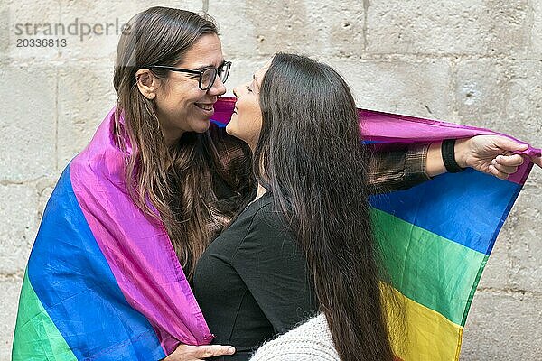 Porträt eines liebevollen jungen lesbischen Paares  das sich umarmt  während es gemeinsam vor einer Steinmauer im Freien steht. Foto in hoher Qualität