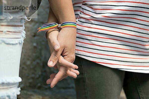 Nahaufnahme eines glücklichen lesbischen Paares  das sich an den Händen hält und ein Armband mit Regenbogenflagge trägt  LGBT Liebeskonzept. Hohe Qualität FullHD Filmmaterial