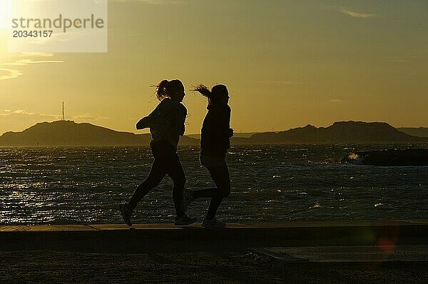 Marseille am Abend  Zwei Jogger laufen bei Sonnenuntergang am Meer entlang  ihre Silhouetten zeichnen sich ab  Marseille  Département Bouches-du-Rhône  Region Provence-Alpes-Côte d'Azur  Frankreich  Europa