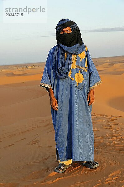 Person in traditioneller Tuareg-Kleidung steht auf einer Sanddüne in der Wüste  Mittlerer Atlas  Marokko  Afrika