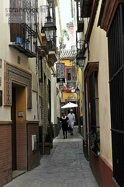 Sevilla  Zwei Personen laufen durch schmale Straße der Altstadt mit historischen Gebäuden  Sevilla  Andalusien  Spanien  Europa