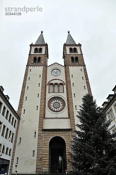 Romanischer UNESCO Kiliansdom  St. Kilian  Dom  Vorderansicht eines Kirchturms mit einer Uhr und zwei spitzen Türmen vor bewölktem Himmel  Würzburg  Unterfranken  Bayern  Deutschland  Europa