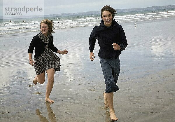 Teenager Zwillingsjunge und mädchen  die lächelnd am Strand laufen  Pembrokeshire  Wales  Vereinigtes Königreich  Modell freigegeben