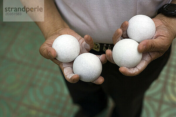 Ein Mann hält vier weiße Bälle in seinen Händen und trainiert sie in Chongqing  China.