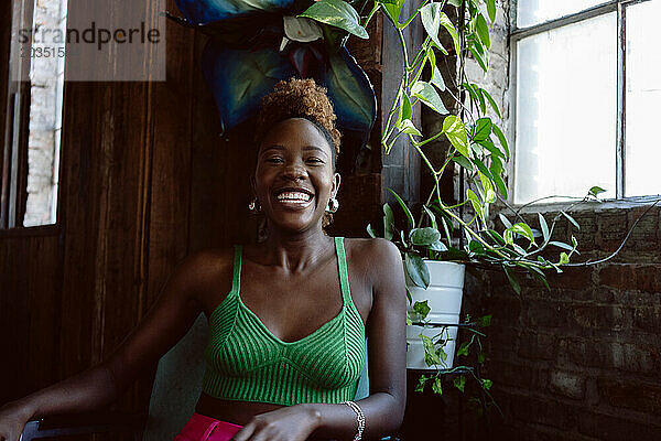 Junge schwarze Frau in farbenfroher Kleidung lächelt lachend in die Kamera
