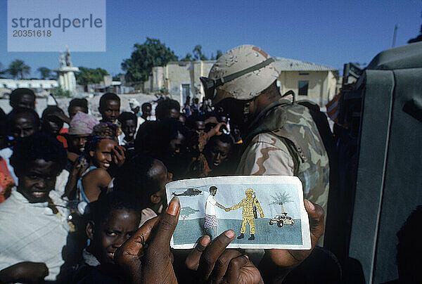 Eine Schar somalischer Kinder versammelt sich um einen Soldaten und verteilt Flugblätter  die die Freundschaft zwischen Somalis und Marines zeigen