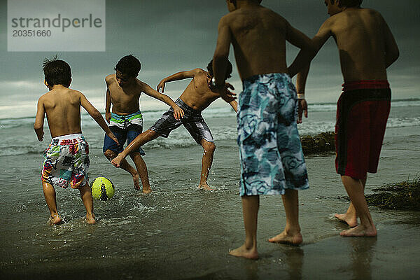 Kinder spielen Fußball am Strand.