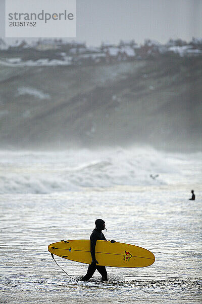 Ein Surfer am Strand von Scarborough.