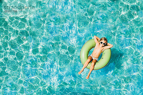 Kleines Kind schwimmt mit Schwimmkörpern im Pool  Foto von oben mit Drohne