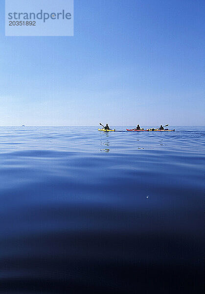Drei Kajakfahrer genießen einen ruhigen Morgen an der Adria vor der Küste von Korcula entlang der dalmatinischen Küste.
