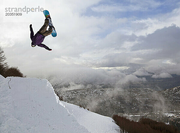 Ein Snowboarder macht einen Sprung und macht einen Backflip am Cerro Catedral in Argentinien